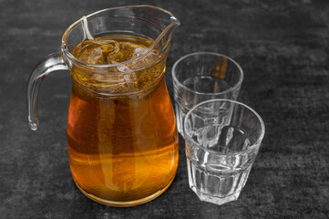 A clear glass jug with a cold drink on the kitchen counter, hot weather