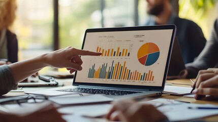 A business meeting with a focus on data analysis, as a laptop screen displays colorful charts and graphs. Team members collaborate and discuss strategies around a table.