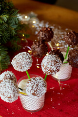 Chocolate cake pops with coconut shavings are displayed in a glass at a celebration, surrounded by festive decorations.
