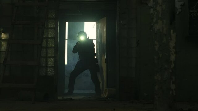 SWAT operator in all black gear and an assault rifle breaching a door in an abandoned warehouse