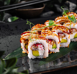 Fresh sushi rolls with eel and avocado being served on black plate