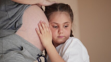 little girl hugs her mother belly. happy family kid pregnancy newborn concept. the daughter lifestyle sent her ear to the belly of the pregnant mother listens to the thrusts dream of the newborn