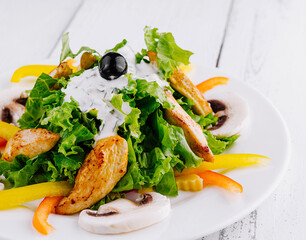 Delicious salad with grilled chicken, mushrooms and yogurt dressing on white wooden table