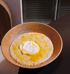 Bowl of creamy polenta with butter and cheese being served in restaurant setting