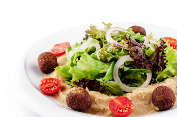 Fresh salad with falafel, hummus, tomatoes and onions on white plate