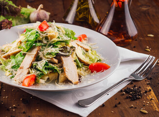 Delicious caesar salad with chicken fillet sitting on wooden table