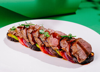 Sliced grilled beef with vegetables lying on white plate