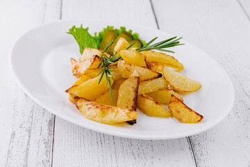 Delicious fried potatoes with rosemary lying on white plate