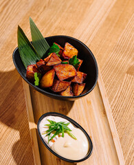 Gourmet fried potato wedges with dip on wooden tray