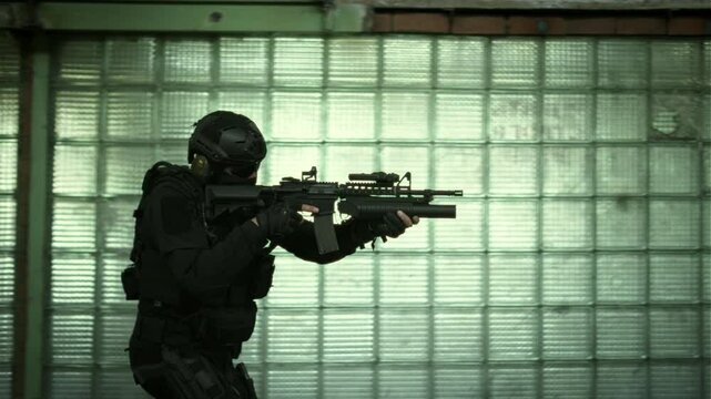 Side follow shot of a Special forces operator in black outfit and an m4 assault rifle with a green laser walking and securing an abandoned building