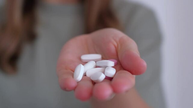 Girl holding pills in her hands, close-up. Treatment of colds during the disease season, healthy lifestyle