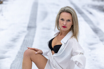 Sexy blonde woman in white underwear and black underwear posing in winter on snow