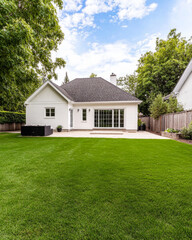 Obraz premium A beautiful suburban home with a spacious backyard and lush green lawn under a blue sky during the daytime