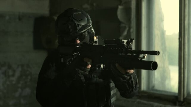 Special forces operator in all black military gear checking his collimator sight on an m4 assault rifle