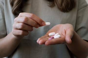 Girl holding pills in her hands, close-up. Treatment of colds during the disease season, healthy lifestyle