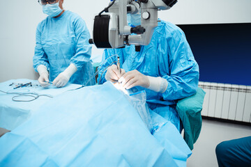 Skilled surgeon and his medical team performs precise eye surgery on an elderly patient, restoring...