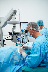 Skilled surgeon and his medical team performs precise eye surgery on an elderly patient, restoring...