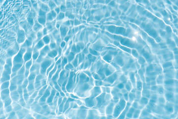 Blue water with ripples on the surface. Defocus blurred transparent blue colored clear calm water surface texture with splashes and bubbles. Water waves with shining pattern texture background.