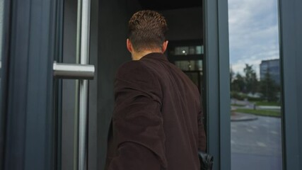 Man entering a modern office building on a sunny day in the city
