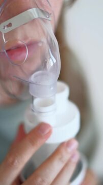 A girl breathes with the help of a nebulizer inhaler for the treatment of colds and coughs during the cold season