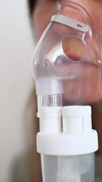 A girl breathes with the help of a nebulizer inhaler for the treatment of colds and coughs during the cold season