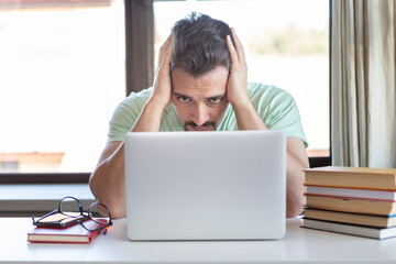 Tired and bored student sitting at the desk while preparing for exams at university	