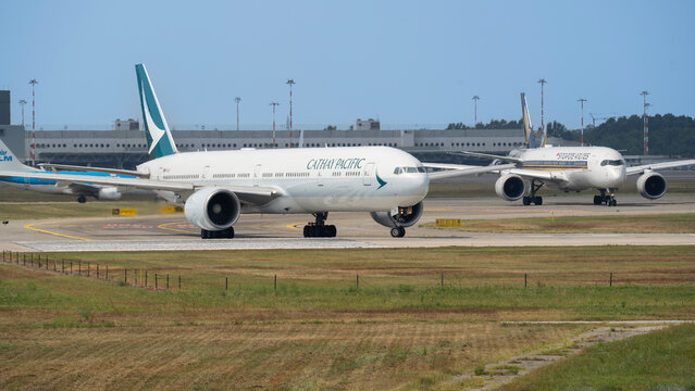 Cathy Pacific and Singapore Airlines airplanes at MXP Milano Malpensa International Airport. Many planes in line waiting to take off. High air traffic