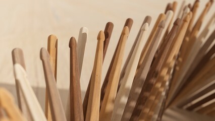Assorted wooden drumsticks displayed on a light brown backdrop, highlighting unique textures and patterns. Ideal for musical endeavors