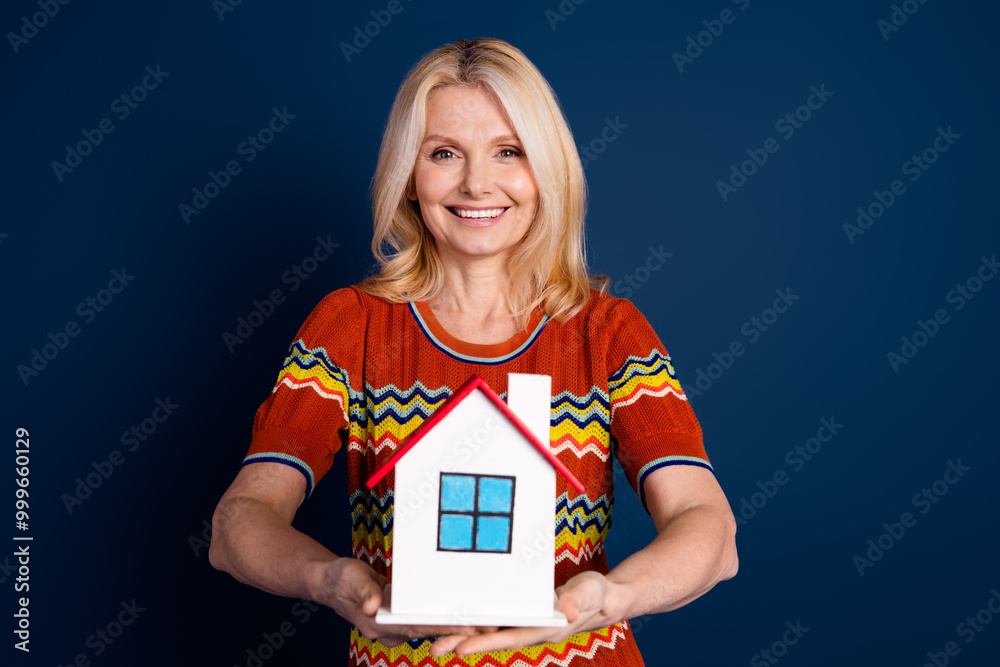 Poster Photo of charming lovely glad senior woman wear striped trendy clothes hold miniature house isolated on dark blue color background