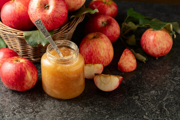 Apple jam and fresh apples on a black stone table.