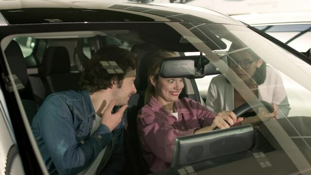 A couple examines options for a new family car in a modern showroom. Their careful selection reflects the importance of finding a vehicle that meets both lifestyle needs and family comfort.