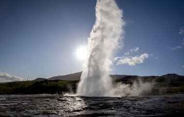 Strokkur geyser erupting in front of the sun, Golden Circle, Iceland