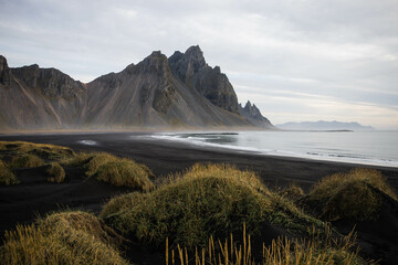 Sunrise Stokksnes cape sea beach and Vestrahorn Mountain with its reflection on wet black volcanic sand surface, Iceland. Amazing nature scenery, popular travel destination.