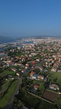 Descent offers sweeping view of Vigo from Samil. Bouzas in front, the port behind, and the city center with the City of Justice building stands out. Rande Bridge and Vigo estuary shine in background.