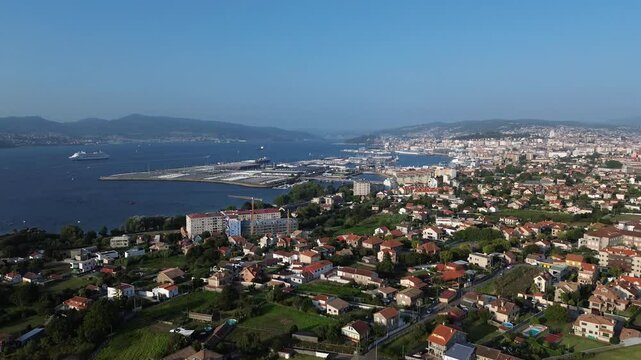 Slow ascent offers view of Vigo from Samil. Alcabre to the left, Bouzas in front, with the port behind. The Vigo estuary shines, featuring cruise ship and the distant Rande Bridge on sunny summer day.