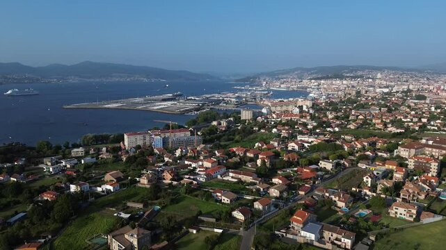 Slow descent offers view of Vigo from Samil. Alcabre to the left, Bouzas in front, with the port behind. The Vigo estuary shines, featuring cruise ship and the distant Rande Bridge on sunny summer day