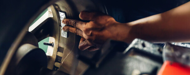 Mechanic using Wheel weights for balancing tires arrayed in trays for precise balance. Repairman Installing Wheel Balance Weight. Mechanic places weights on steel rim of machine. Balance wheel in car © kanpisut