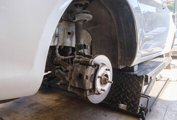 Close-up view of a car's brake disc and caliper during maintenance in a garage.