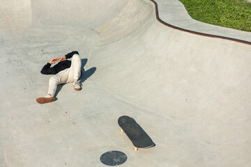 Hurt skater lying on the ground after falling from skateboard due to hitting a manhole cover