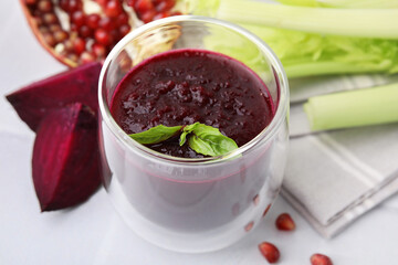 Fresh beetroot smoothie with mint in glass on white table, closeup