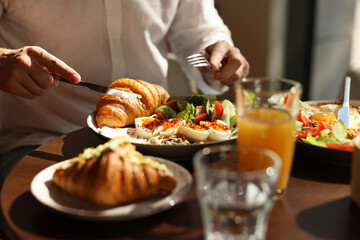 Man having tasty breakfast at wooden table in cafe, closeup