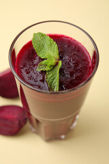 Fresh beetroot smoothie with mint in glass on beige background, closeup