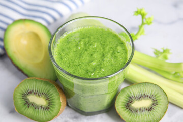 Delicious green smoothie and ingredients on white table, closeup