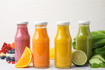 Glass bottles of tasty smoothies and different products on white table