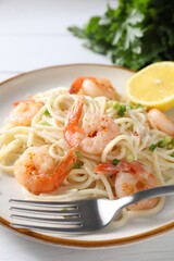 Delicious pasta with shrimps, green onion and fork on white table, closeup