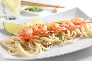 Delicious pasta with shrimps, green onions and lime on white table, closeup