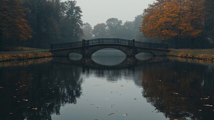 Fototapeta premium A serene bridge over a calm river surrounded by autumn foliage.