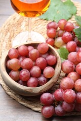 Fresh ripe grapes and glass of wine on wooden table, closeup