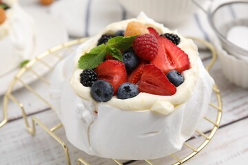 Pavlova cake (meringue dessert) with whipped cream, fresh berries and mint on white wooden table, closeup