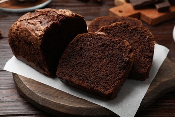 Delicious cut chocolate sponge cake on wooden table, closeup